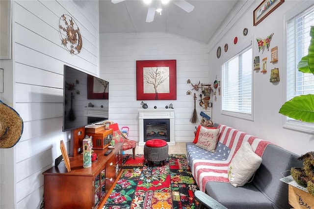 living room featuring ceiling fan, lofted ceiling, and wood walls