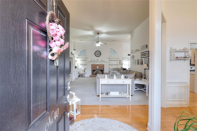 entrance foyer with ceiling fan, light wood-type flooring, and a fireplace