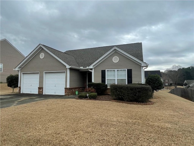 ranch-style house with driveway, brick siding, roof with shingles, an attached garage, and a front yard