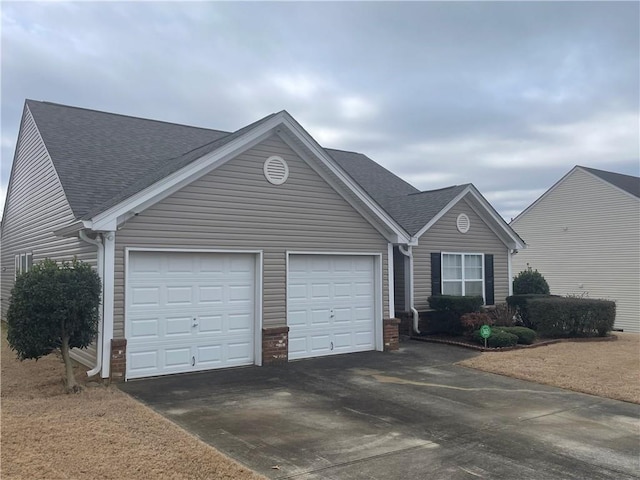 single story home featuring a garage, concrete driveway, and roof with shingles