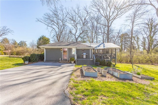 view of front of house with driveway, a vegetable garden, and a front yard