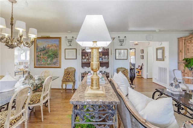 dining room with an inviting chandelier, crown molding, light wood-style flooring, and visible vents