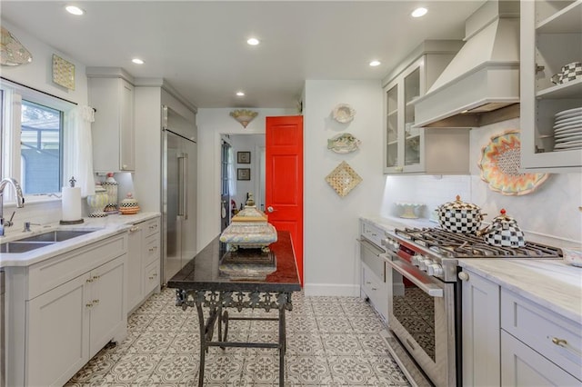 kitchen with premium range hood, high quality appliances, decorative backsplash, recessed lighting, and a sink