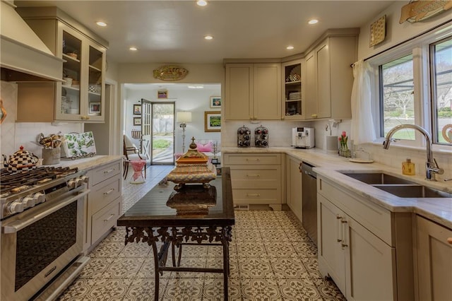 kitchen with tasteful backsplash, custom range hood, recessed lighting, appliances with stainless steel finishes, and a sink