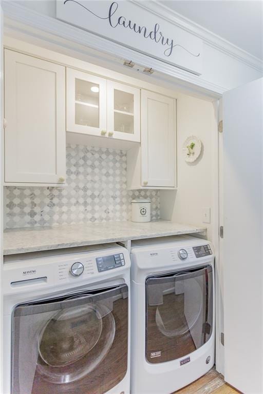 laundry area featuring cabinet space, washer and dryer, and ornamental molding