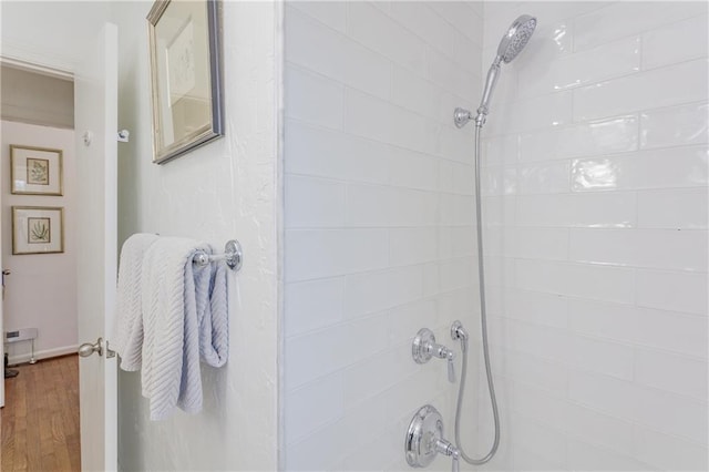 full bathroom with wood finished floors and tiled shower