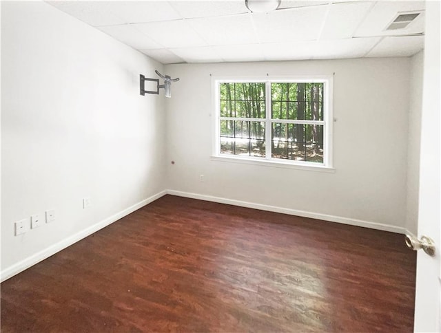 empty room featuring dark wood-type flooring and a drop ceiling