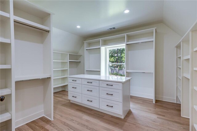 spacious closet featuring light hardwood / wood-style floors and vaulted ceiling