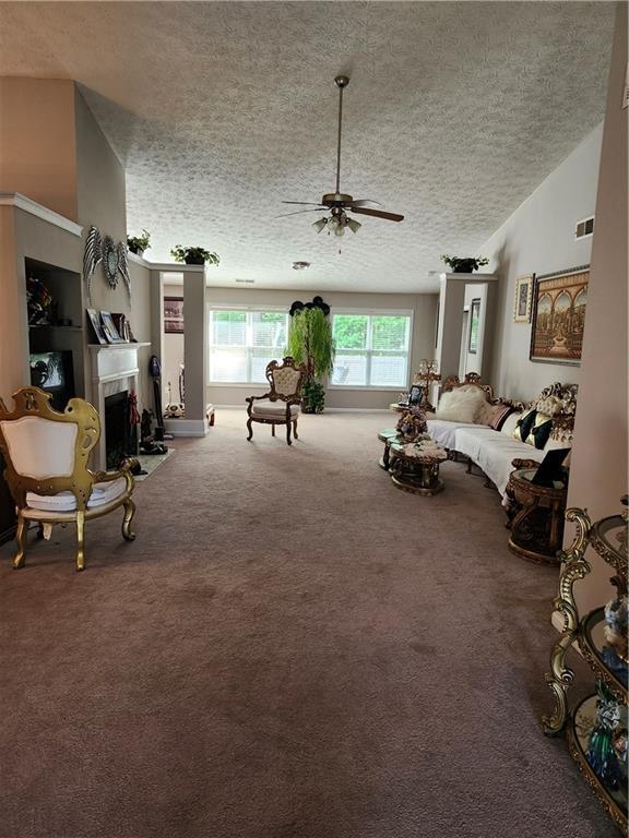 979 Simonton Glen Dr, Lawrenceville, GA 30045 - living area featuring a textured ceiling, ceiling fan, carpet, a fireplace, and vaulted ceiling