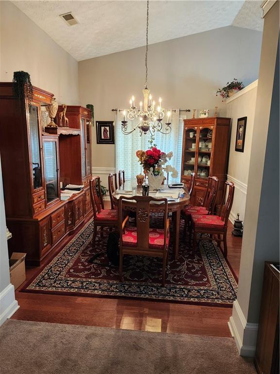 979 Simonton Glen Dr, Lawrenceville, GA 30045 - dining room featuring lofted ceiling, a chandelier, a textured ceiling, and carpet