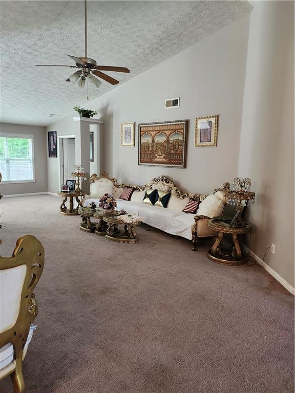 979 Simonton Glen Dr, Lawrenceville, GA 30045 - living room featuring a textured ceiling, carpet floors, vaulted ceiling, and a ceiling fan