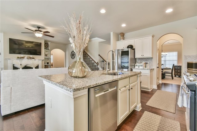 kitchen with open floor plan, ceiling fan with notable chandelier, arched walkways, and appliances with stainless steel finishes