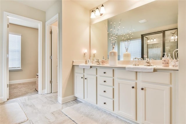 full bath featuring a shower stall, double vanity, baseboards, and a sink