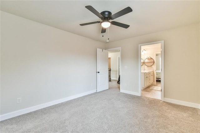 unfurnished bedroom featuring light carpet, ensuite bath, baseboards, and a ceiling fan