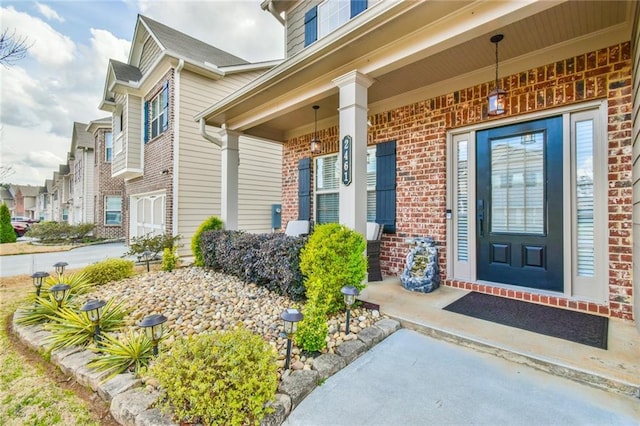 view of exterior entry with brick siding and covered porch