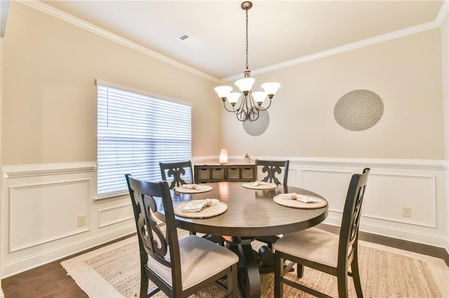 dining area featuring crown molding, an inviting chandelier, and wood finished floors