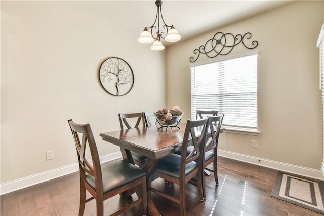 dining space with dark wood finished floors, a notable chandelier, and baseboards