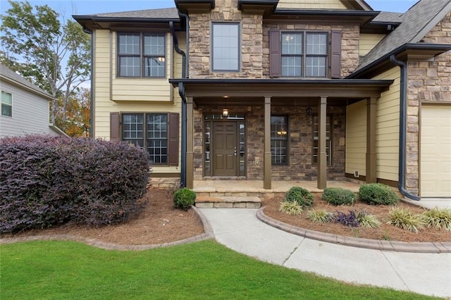 view of exterior entry featuring covered porch and a garage