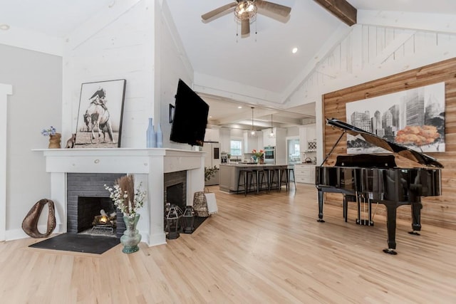 6044 Wade Orr Rd, Flowery Branch, GA 30542 - living room featuring a warm lit fireplace, light wood-style floors, a ceiling fan, beamed ceiling, and high vaulted ceiling