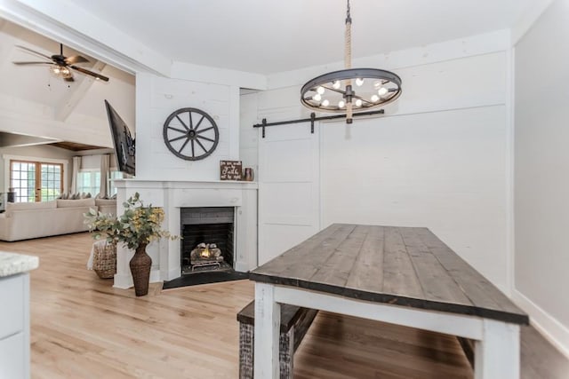 6044 Wade Orr Rd, Flowery Branch, GA 30542 - dining room with ceiling fan, wood finished floors, a barn door, a chandelier, and a fireplace with flush hearth