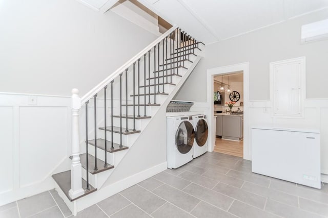 6044 Wade Orr Rd, Flowery Branch, GA 30542 - washroom featuring washer and dryer, light tile patterned flooring, a decorative wall, and a wainscoted wall