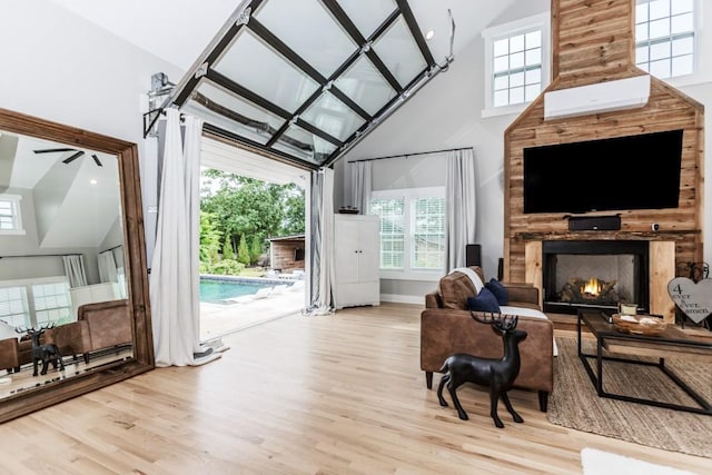 6044 Wade Orr Rd, Flowery Branch, GA 30542 - living area featuring high vaulted ceiling, wood finished floors, a fireplace, and healthy amount of natural light