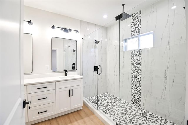 full bath with a marble finish shower, wood finished floors, and vanity