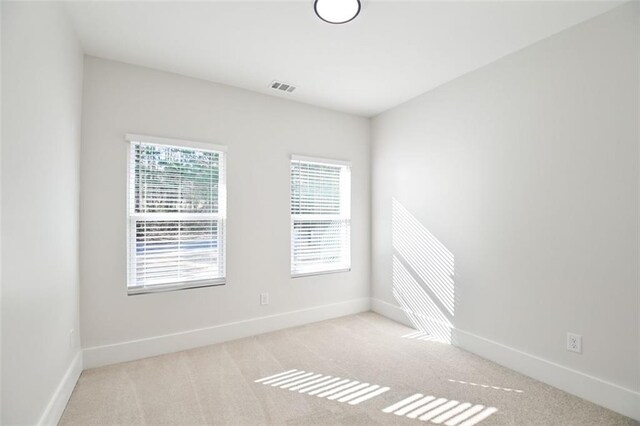 carpeted spare room with visible vents and baseboards