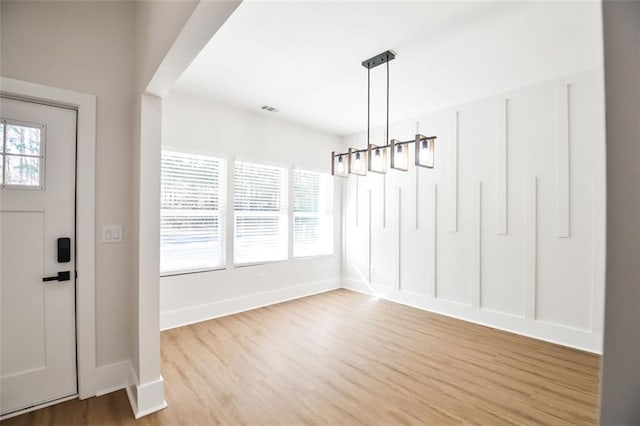 unfurnished dining area featuring plenty of natural light, baseboards, and wood finished floors