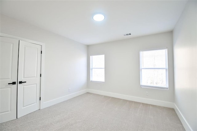 unfurnished room featuring visible vents, baseboards, and light colored carpet