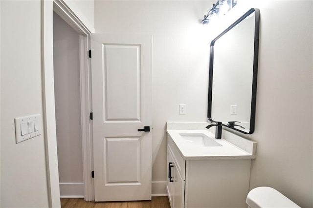 bathroom with vanity, toilet, and wood finished floors