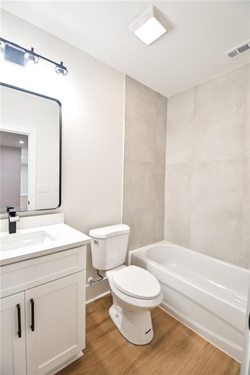 bathroom featuring visible vents, toilet, wood finished floors,  shower combination, and vanity