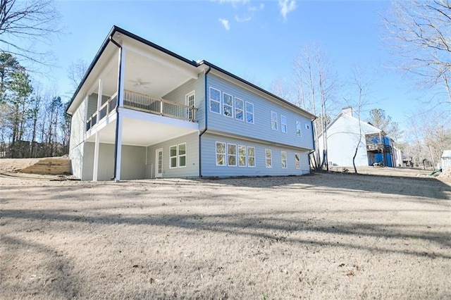 back of house with driveway, a balcony, and ceiling fan