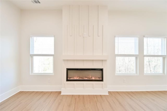 unfurnished living room featuring baseboards, a fireplace, and light wood-style floors