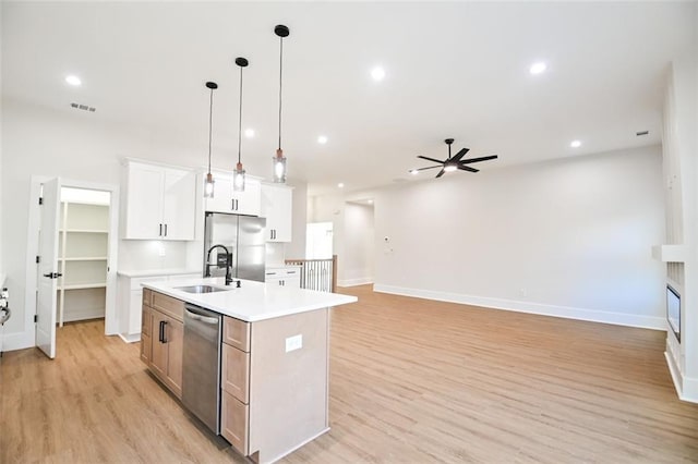 kitchen featuring a kitchen island with sink, stainless steel appliances, visible vents, light wood-style floors, and light countertops