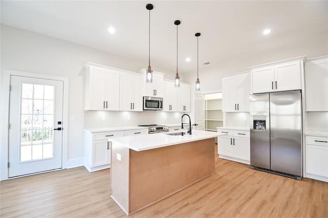 kitchen with stainless steel appliances, light wood finished floors, a sink, and light countertops