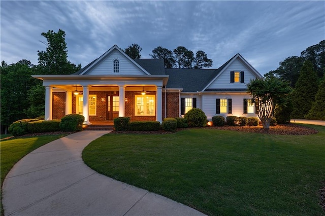view of front of home with a porch, brick siding, and a front yard