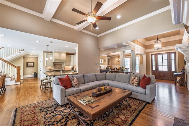 living room with a ceiling fan, ornamental molding, light wood-style flooring, and stairway