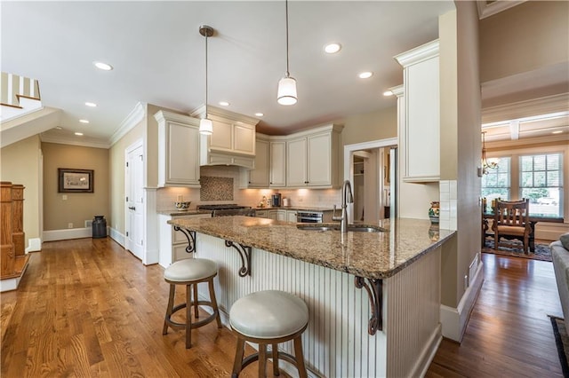 kitchen featuring dark stone counters, backsplash, crown molding, and a sink