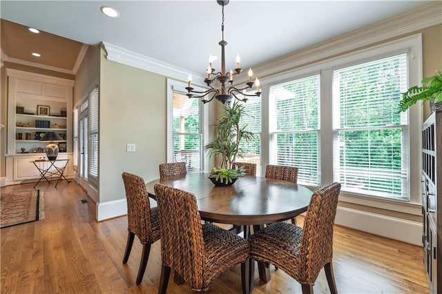 dining room with crown molding, a chandelier, plenty of natural light, and light wood-style floors