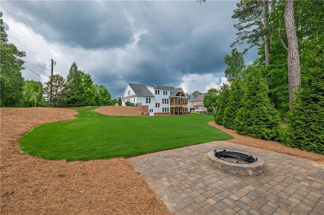 rear view of property featuring a fire pit, a patio area, and a yard