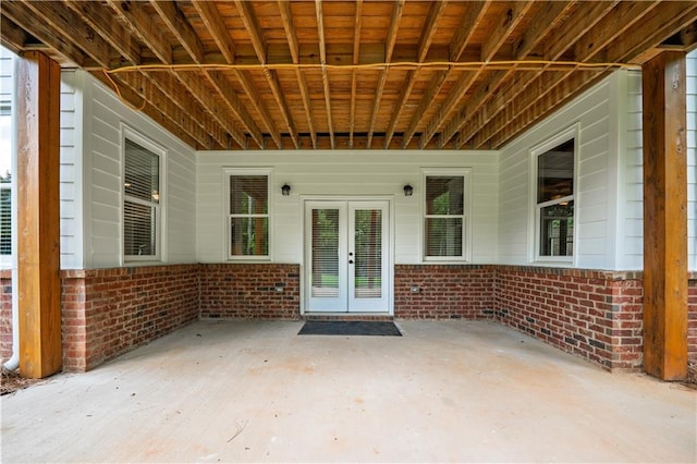 property entrance featuring french doors, a patio, and brick siding