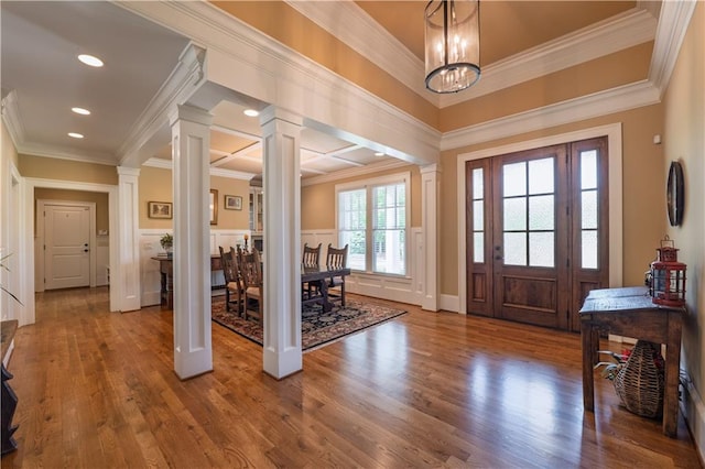 foyer with crown molding, ornate columns, and wood finished floors