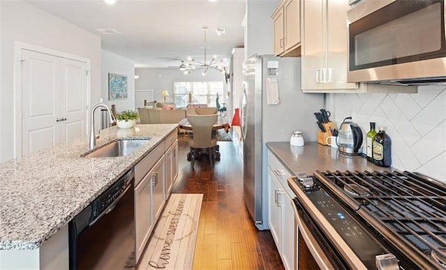 kitchen featuring decorative backsplash, stainless steel appliances, dark wood-type flooring, sink, and a notable chandelier