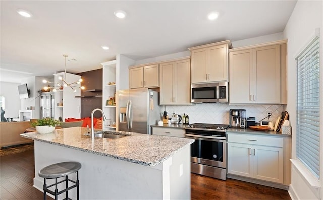 kitchen with light stone countertops, appliances with stainless steel finishes, decorative backsplash, sink, and hanging light fixtures