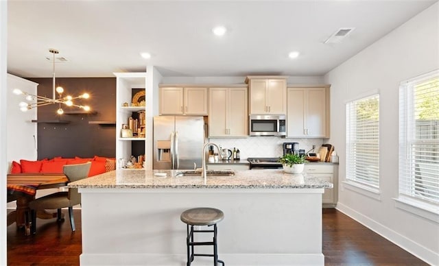 kitchen featuring pendant lighting, sink, light stone countertops, and stainless steel appliances