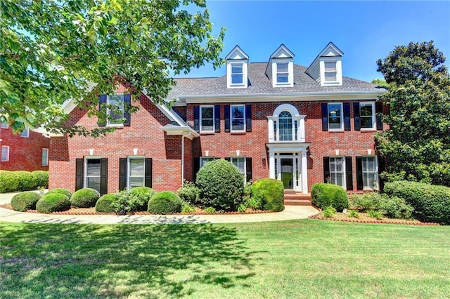 colonial-style house featuring a front yard and brick siding