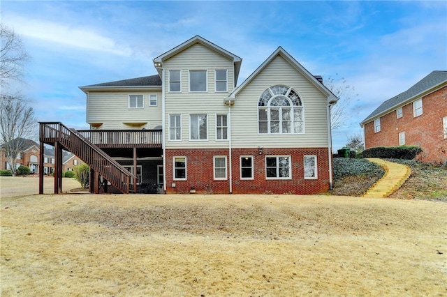 rear view of property with stairway, brick siding, and a wooden deck