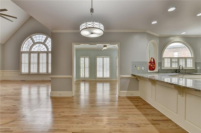 empty room featuring light wood-style flooring, baseboards, ceiling fan, and ornamental molding