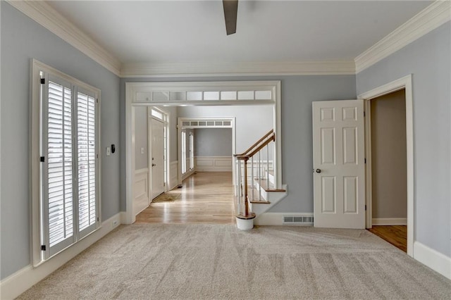 foyer entrance with visible vents, stairs, a towering ceiling, wood finished floors, and a decorative wall